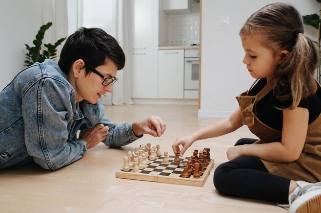 young dad playing chess on the floor with his daughter, quality parent-child interaction